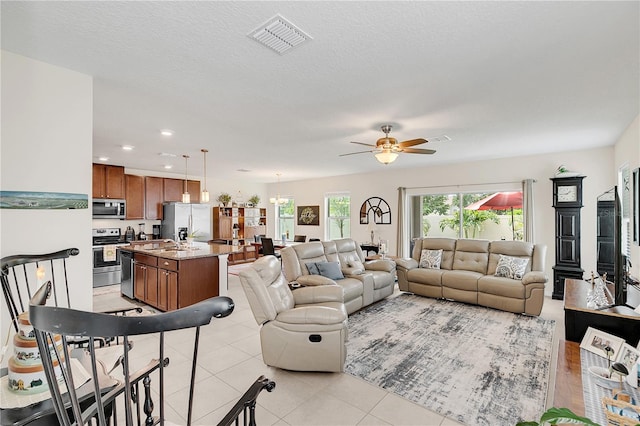 living room featuring sink, light tile patterned floors, a textured ceiling, and ceiling fan