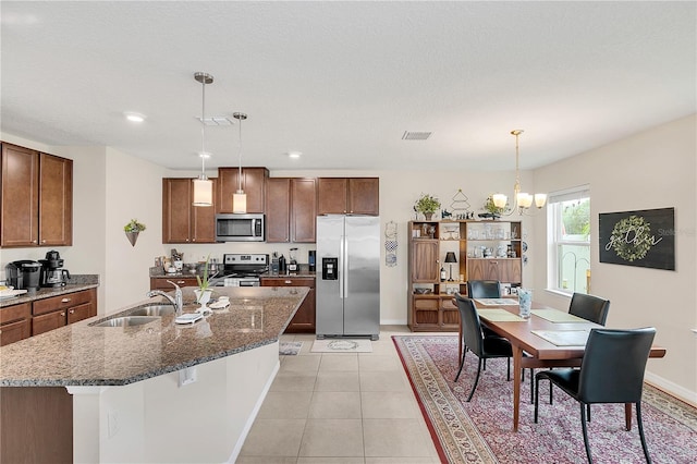 kitchen with sink, light tile patterned flooring, decorative light fixtures, and stainless steel appliances