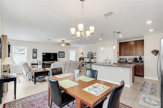 tiled dining area with sink, a textured ceiling, and ceiling fan with notable chandelier