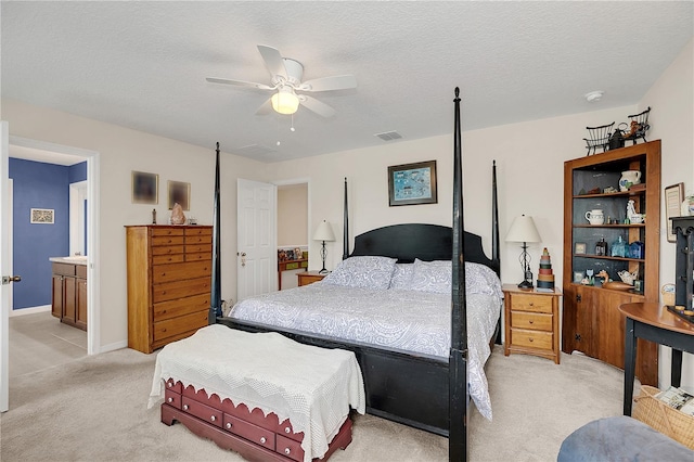 bedroom featuring light colored carpet, a textured ceiling, ceiling fan, and connected bathroom