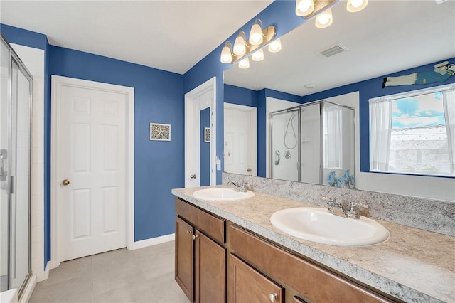 bathroom featuring dual vanity, a shower with shower door, and tile patterned flooring