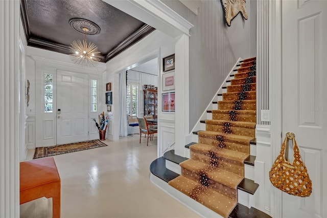 entrance foyer featuring crown molding, a chandelier, a textured ceiling, and concrete floors