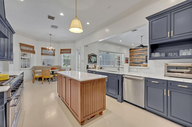 kitchen with sink, decorative light fixtures, appliances with stainless steel finishes, a kitchen island, and light stone countertops