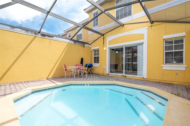 view of swimming pool with glass enclosure and a patio area