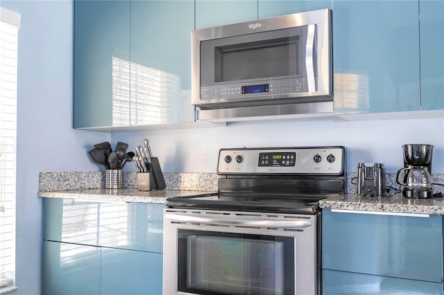 kitchen featuring appliances with stainless steel finishes, blue cabinets, and light stone counters