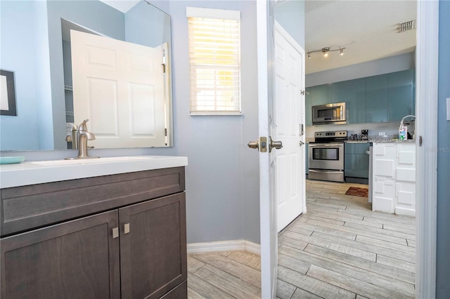 bathroom with track lighting, vanity, and hardwood / wood-style floors