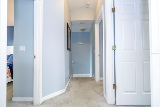 hallway with lofted ceiling and light carpet