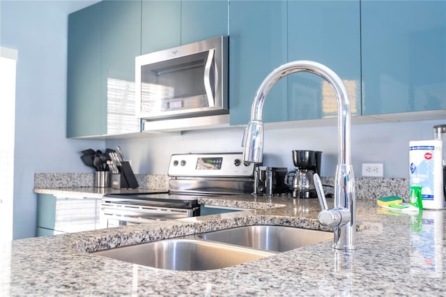 kitchen featuring blue cabinetry, stainless steel appliances, and stone counters