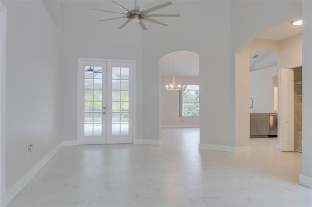 unfurnished room with ceiling fan with notable chandelier, high vaulted ceiling, and french doors