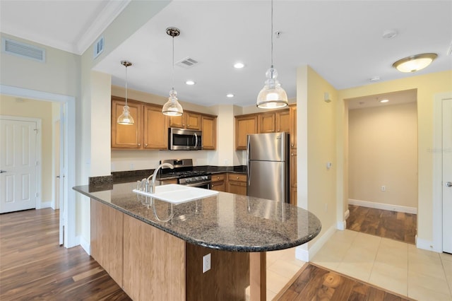 kitchen with kitchen peninsula, decorative light fixtures, dark stone counters, and stainless steel appliances