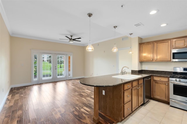 kitchen featuring crown molding, kitchen peninsula, sink, decorative light fixtures, and stainless steel appliances