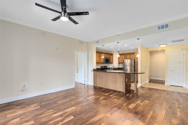 kitchen featuring pendant lighting, light hardwood / wood-style flooring, ceiling fan, appliances with stainless steel finishes, and a breakfast bar