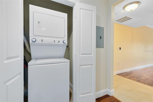 washroom with tile patterned floors, stacked washer / drying machine, and electric panel