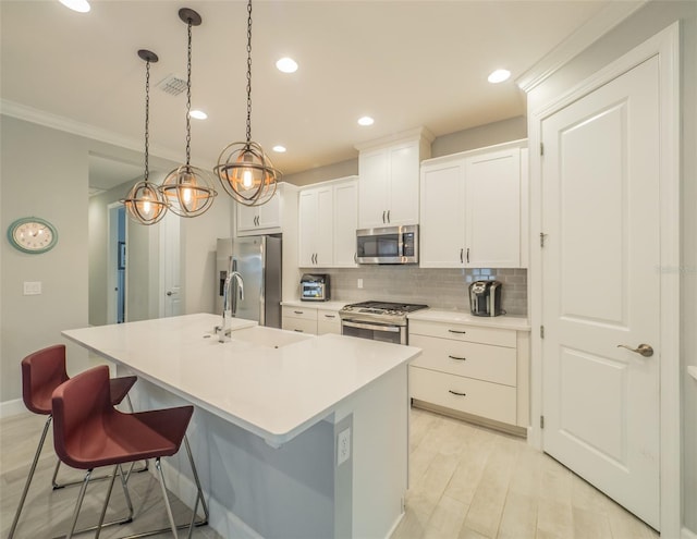 kitchen with a breakfast bar, white cabinetry, appliances with stainless steel finishes, pendant lighting, and a kitchen island with sink