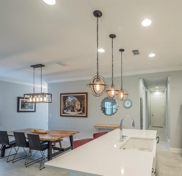 kitchen with a kitchen island with sink, sink, and hanging light fixtures