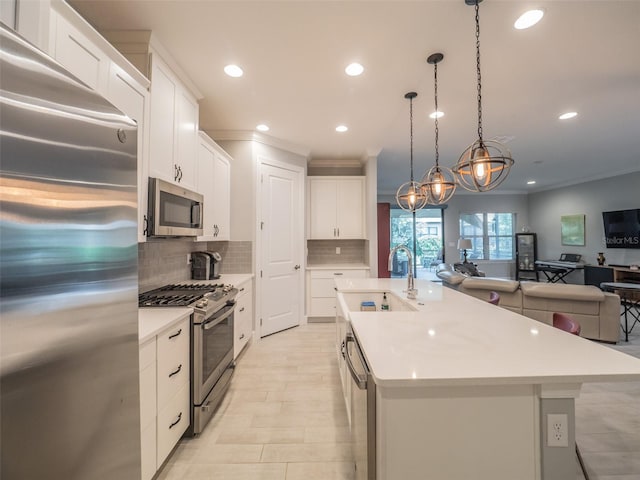 kitchen featuring pendant lighting, sink, white cabinets, a kitchen island with sink, and stainless steel appliances