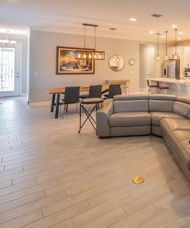 living room featuring an inviting chandelier, crown molding, and light hardwood / wood-style floors