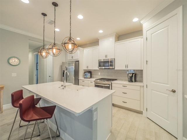 kitchen with white cabinetry, hanging light fixtures, a center island with sink, stainless steel appliances, and a kitchen bar