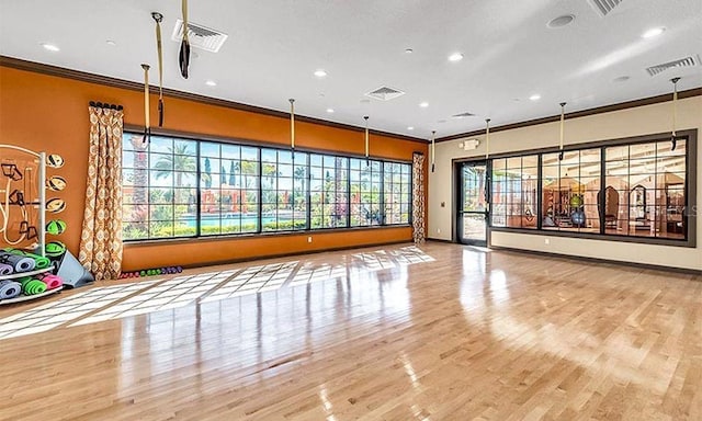 exercise area with ornamental molding and light hardwood / wood-style floors