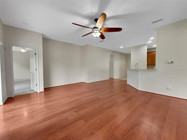 unfurnished living room featuring ceiling fan, light hardwood / wood-style flooring, and sink