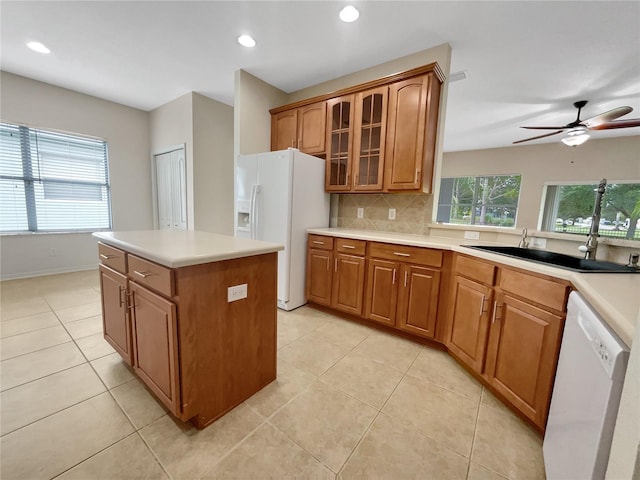 kitchen with tasteful backsplash, ceiling fan, a kitchen island, sink, and white appliances