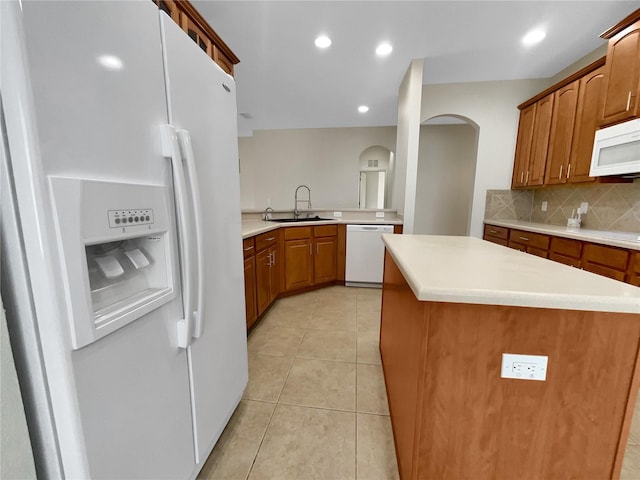 kitchen with white appliances, a center island, tasteful backsplash, sink, and light tile patterned floors