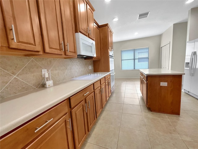 kitchen with backsplash, white appliances, light tile patterned floors, and a kitchen island