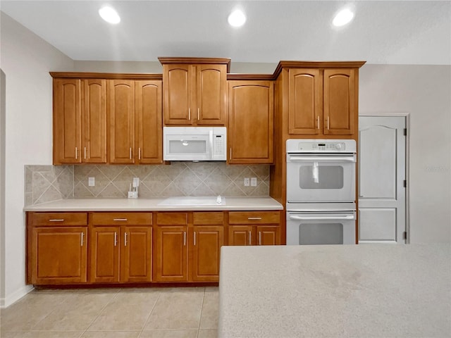 kitchen with white appliances, light tile patterned floors, and tasteful backsplash