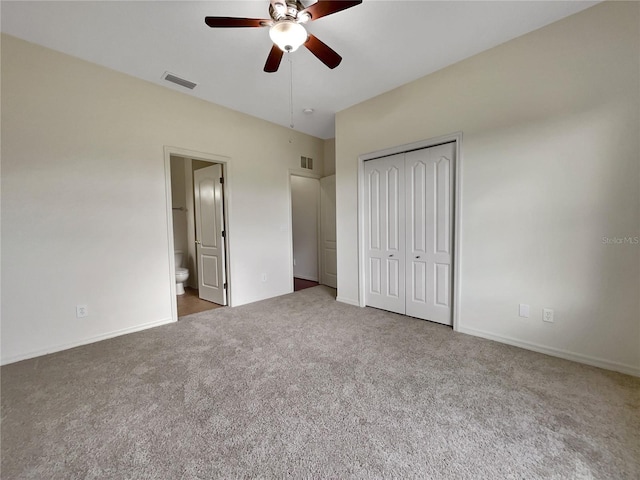 unfurnished bedroom featuring ceiling fan, a closet, ensuite bath, and dark colored carpet