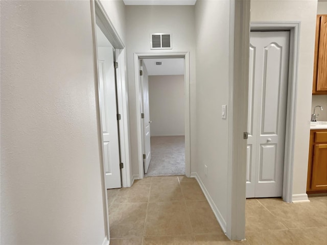 hall with light colored carpet and sink