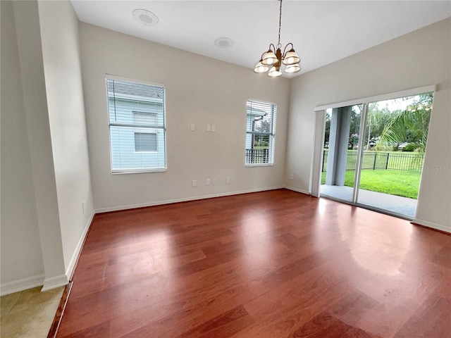 empty room with hardwood / wood-style floors and an inviting chandelier