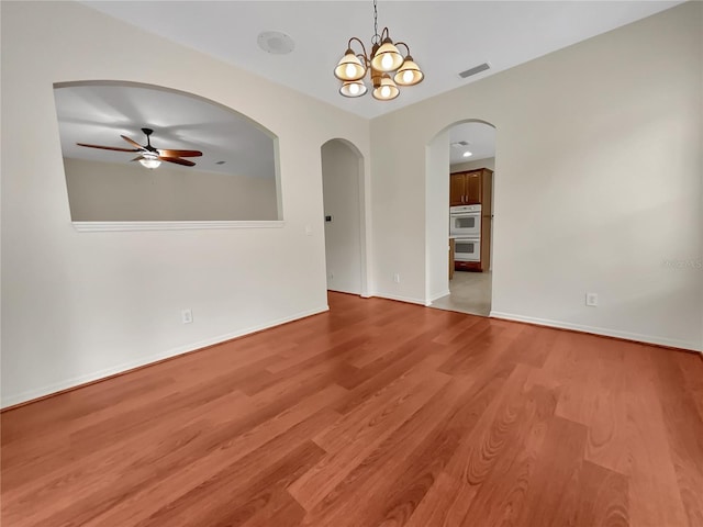 empty room featuring ceiling fan with notable chandelier and light hardwood / wood-style floors