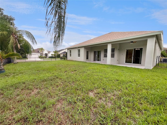 rear view of property with ceiling fan, a lawn, and a patio