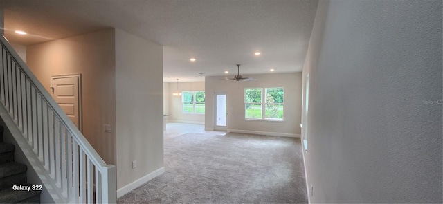 hall featuring light colored carpet and a textured ceiling