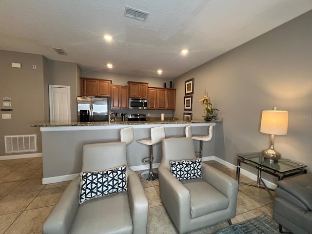 kitchen featuring stainless steel appliances, dark stone countertops, a kitchen breakfast bar, and a spacious island