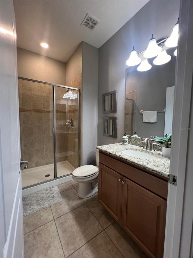 bathroom featuring tile patterned floors, vanity, toilet, and a shower with shower door