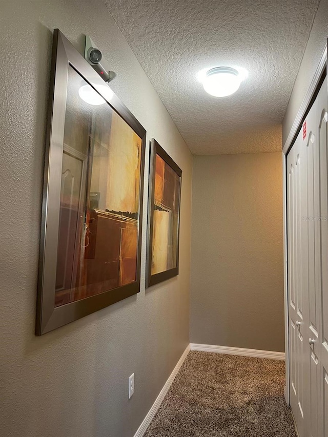 hallway featuring carpet floors and a textured ceiling