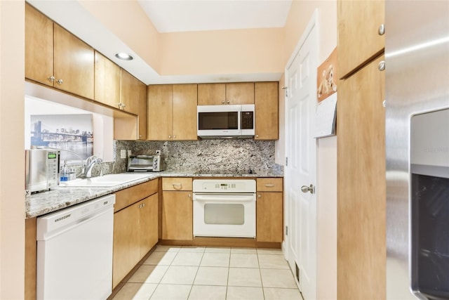 kitchen with light tile patterned floors, sink, white appliances, light stone countertops, and decorative backsplash