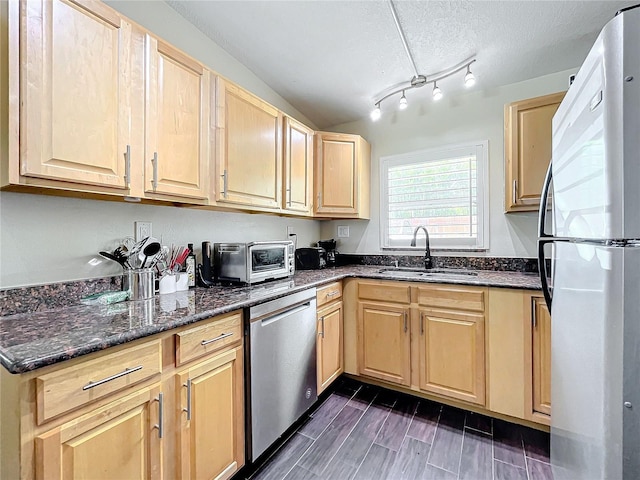 kitchen with sink, stainless steel appliances, dark stone countertops, and light brown cabinets