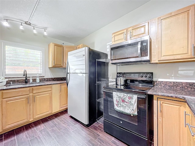 kitchen with light brown cabinets, sink, a textured ceiling, dark stone countertops, and stainless steel appliances