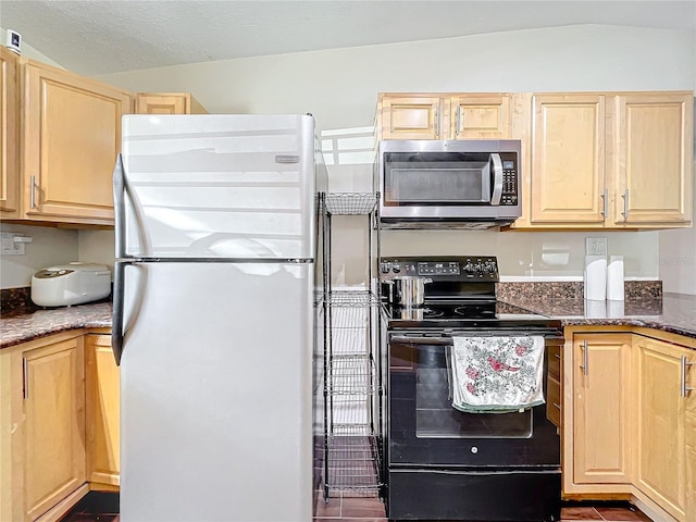 kitchen featuring refrigerator, light brown cabinetry, dark stone counters, black electric range, and lofted ceiling