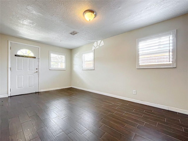 foyer with dark wood-type flooring and a textured ceiling