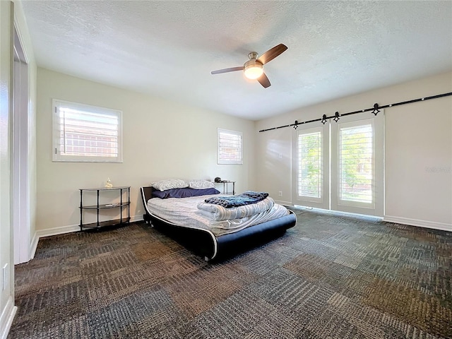 bedroom with ceiling fan, dark colored carpet, and a textured ceiling