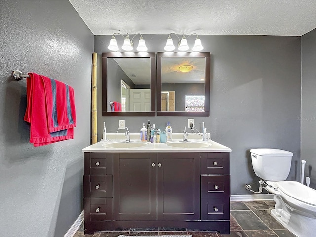 bathroom with a textured ceiling, toilet, and vanity