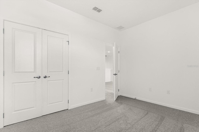 unfurnished bedroom featuring a closet and light colored carpet