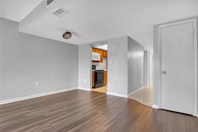 unfurnished living room with a textured ceiling and light hardwood / wood-style floors