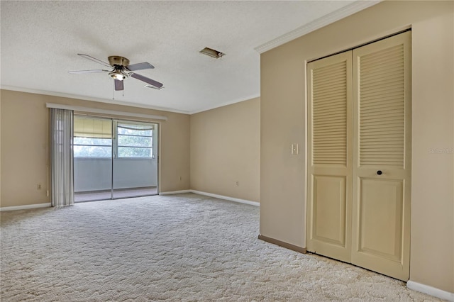 unfurnished bedroom featuring ornamental molding, ceiling fan, light carpet, a textured ceiling, and a closet