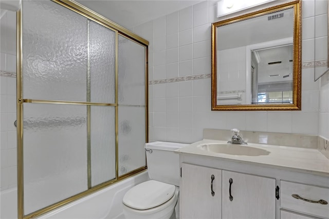 full bathroom featuring toilet, shower / bath combination with glass door, tile walls, vanity, and backsplash