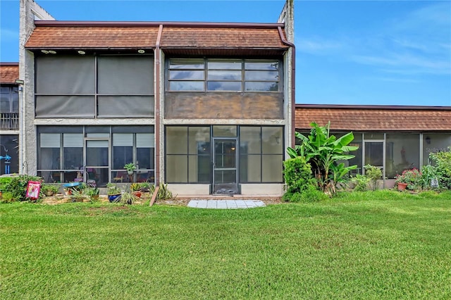 back of property featuring a sunroom and a yard