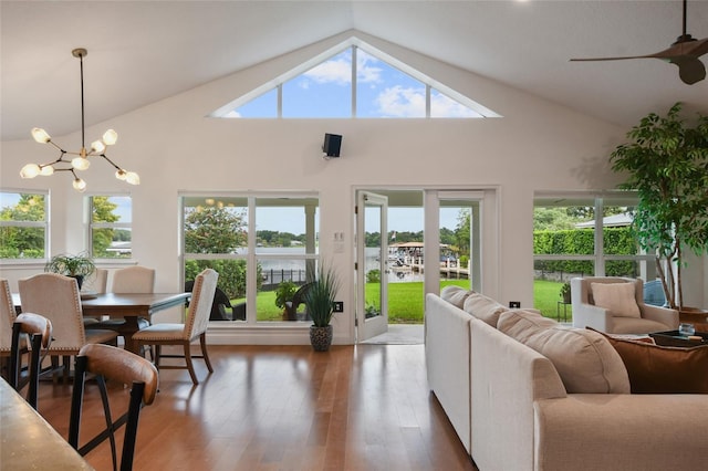 sunroom with ceiling fan with notable chandelier and vaulted ceiling